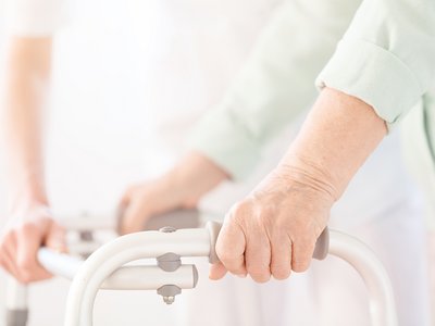 Close-up of senior person uses walking frame during rehabilitation at home Schlaganfall.jpg